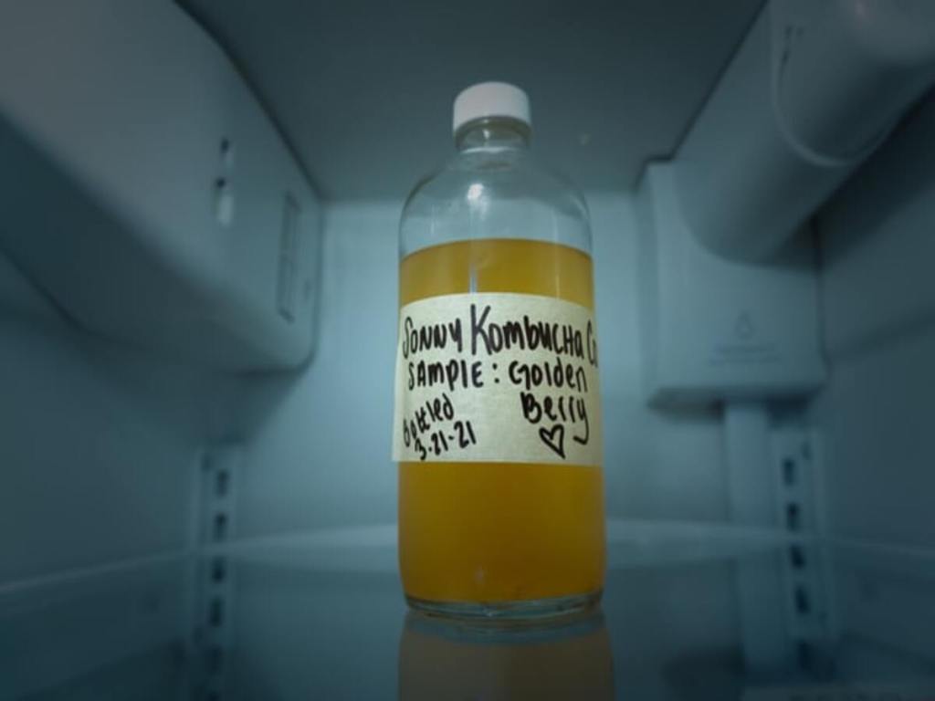A labeled and tagged bottle of kombucha.
