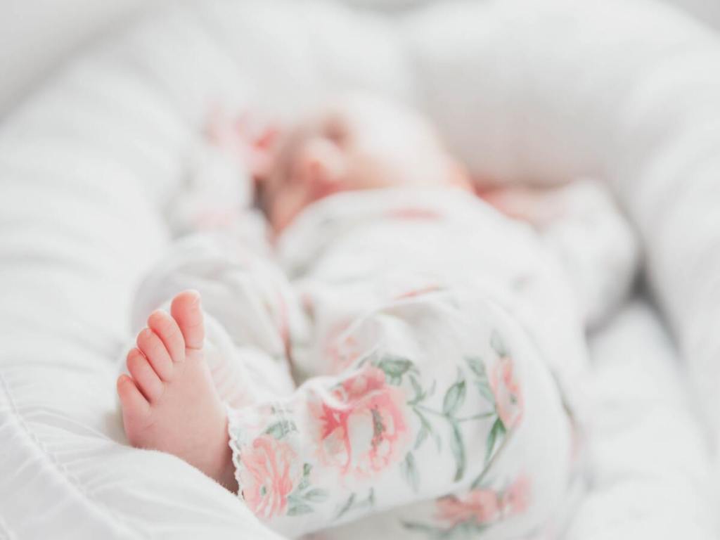 Sleeping baby surrounded by white pillows.