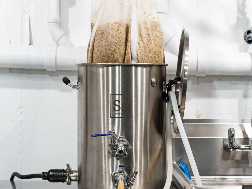 A bag of crushed grains hanging over a kettle.