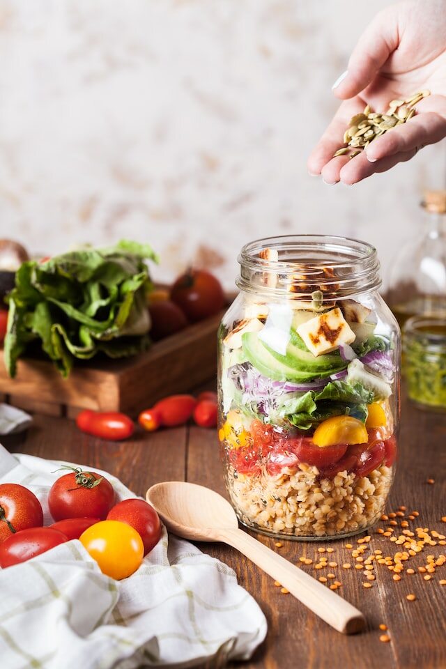 Adding spices to the jar with vegetables and seeds.