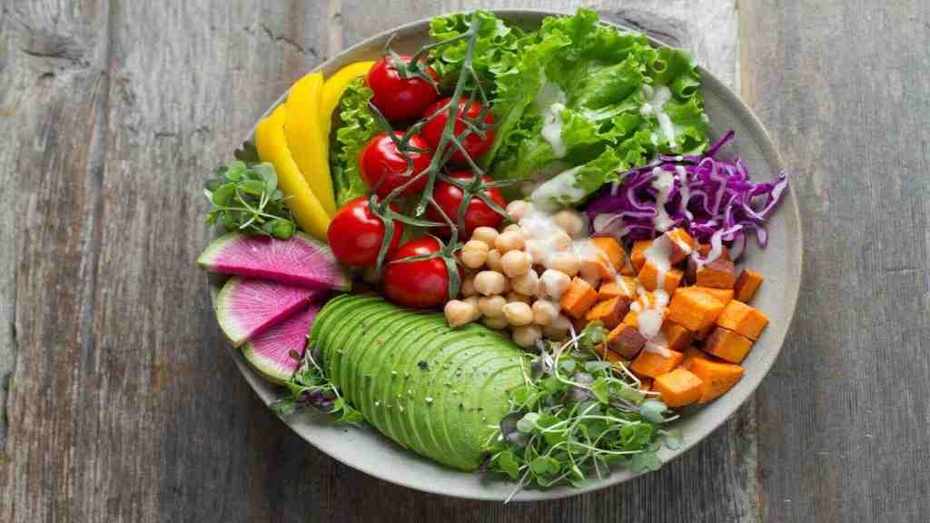 Lettuce, tomatoes, avocado, and other healthy food on a plate.