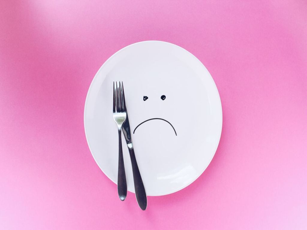 An angry face on a white plate and pink background.
