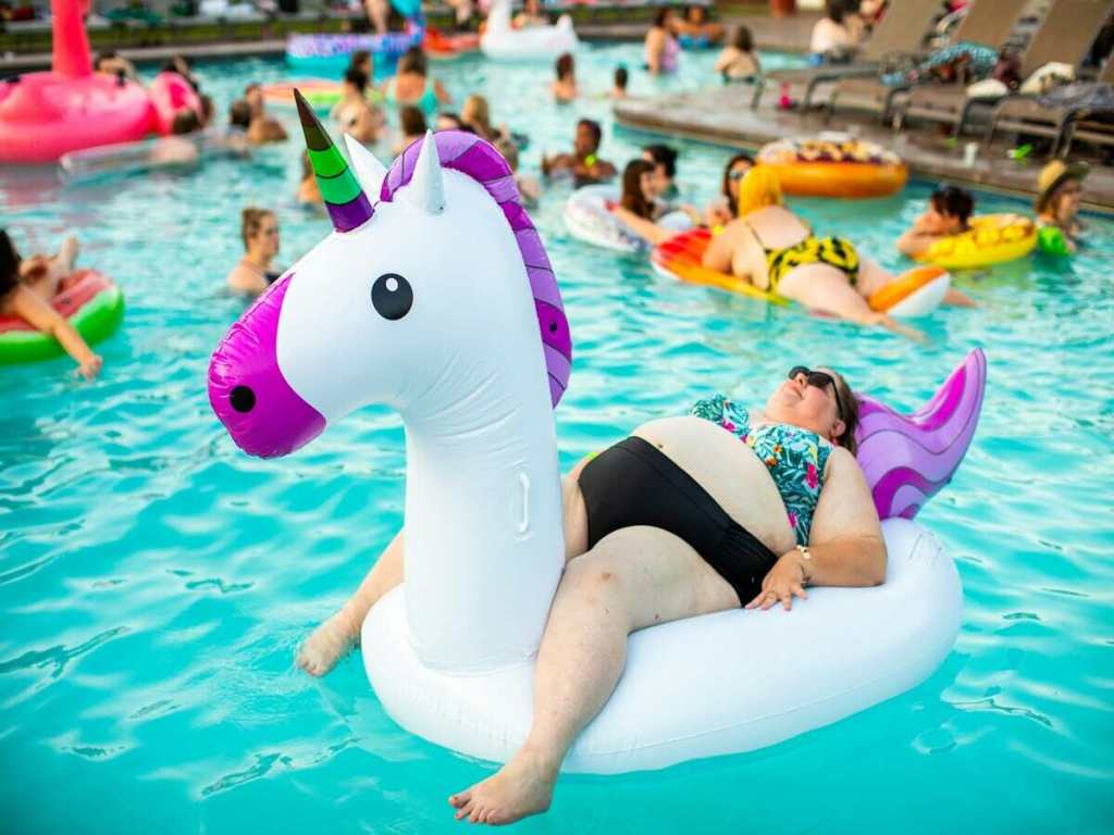 A woman resting on a unicorn floating in a waterpark.