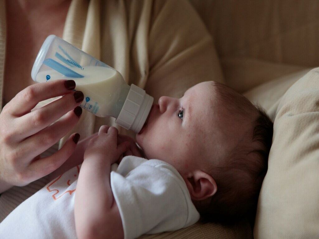 A baby drinking milk from a bottle.