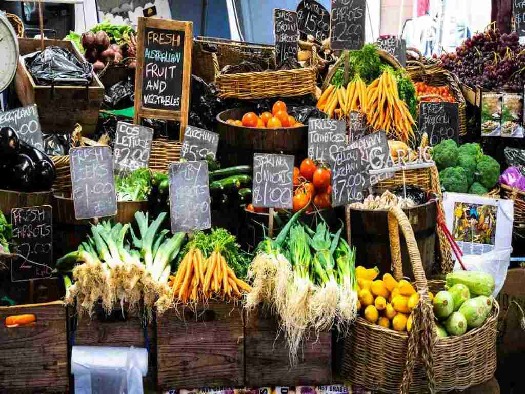 Fruits and vegetables are displayed for sale with prices.