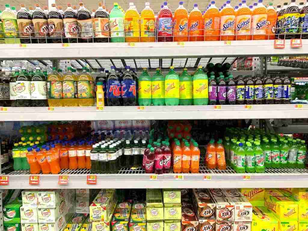 Different brands of soda are on supermarket shelves.