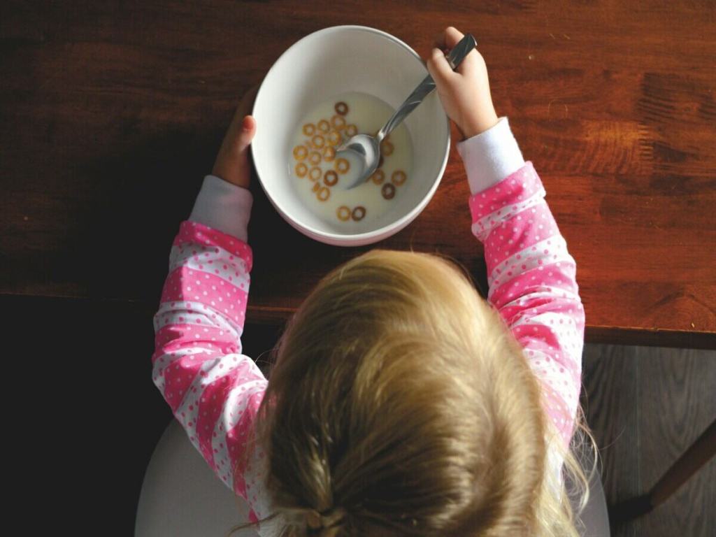 A little girl eating cereals with milk.