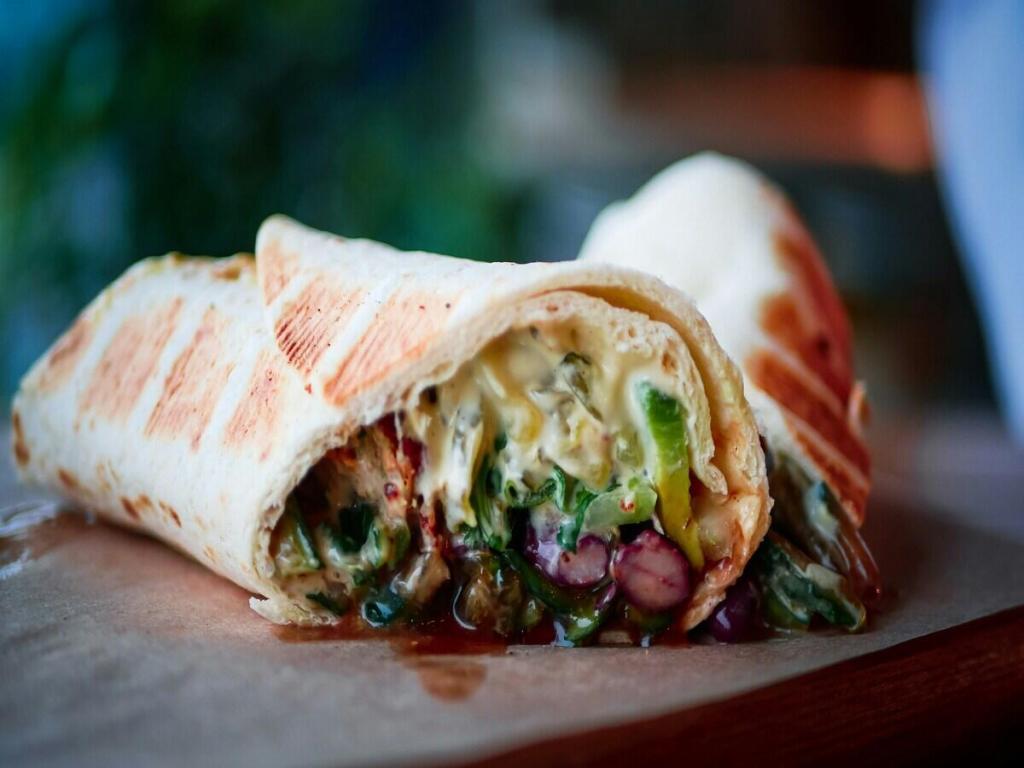A vegan wrap with vegetables and white sauce.
